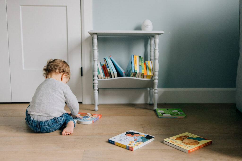 Toddler reading books in room during in home family photography session in Chatham-Kent Ontario